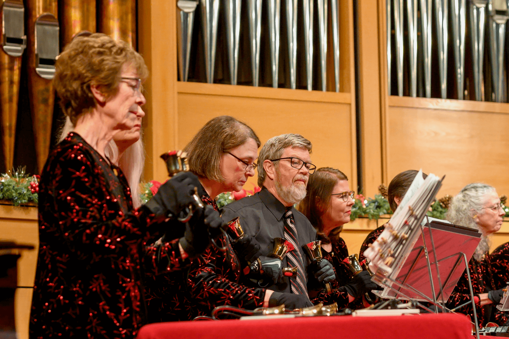 several people ringing handbells wearing red and black joyful colors