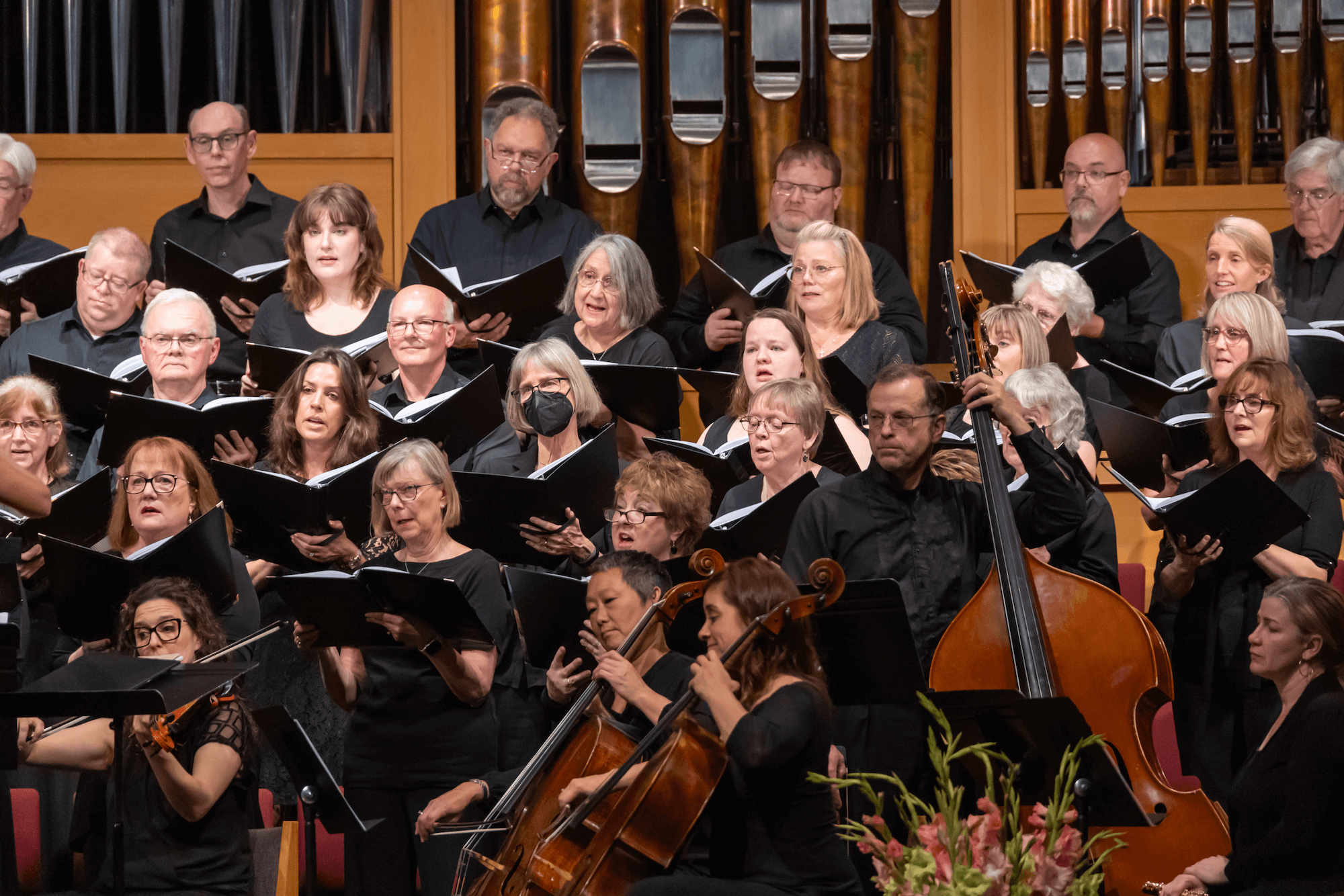 members of the sanctuary choir dressed in black and singing with several string instruments in the foreground