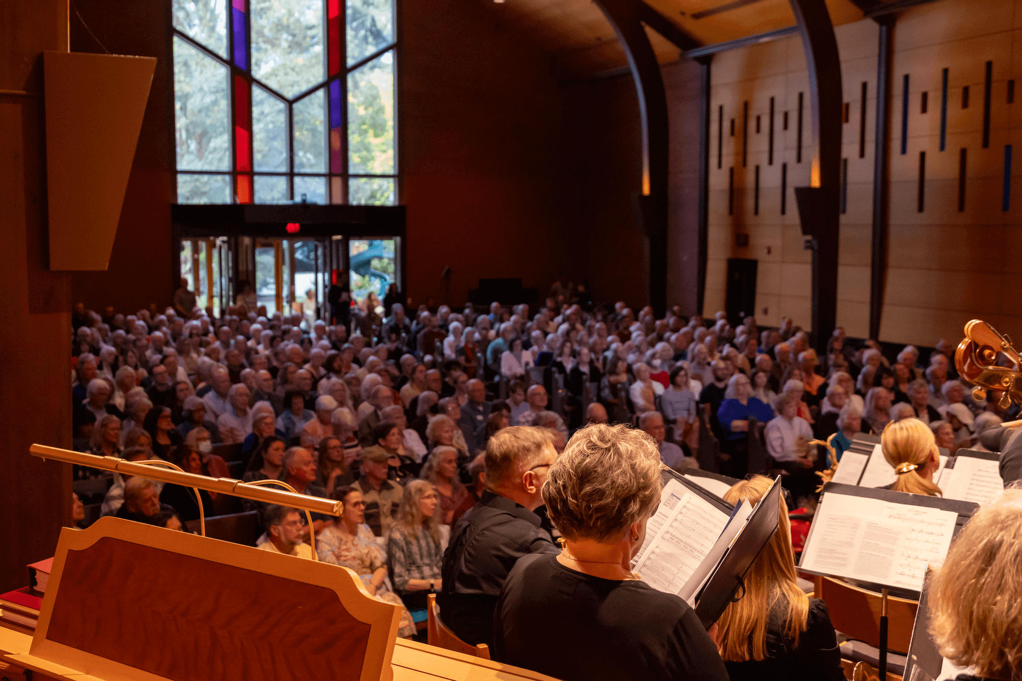 a wide view of a full audience from behind an organ console