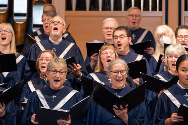 a close up view of several choir members singing with joyful faces