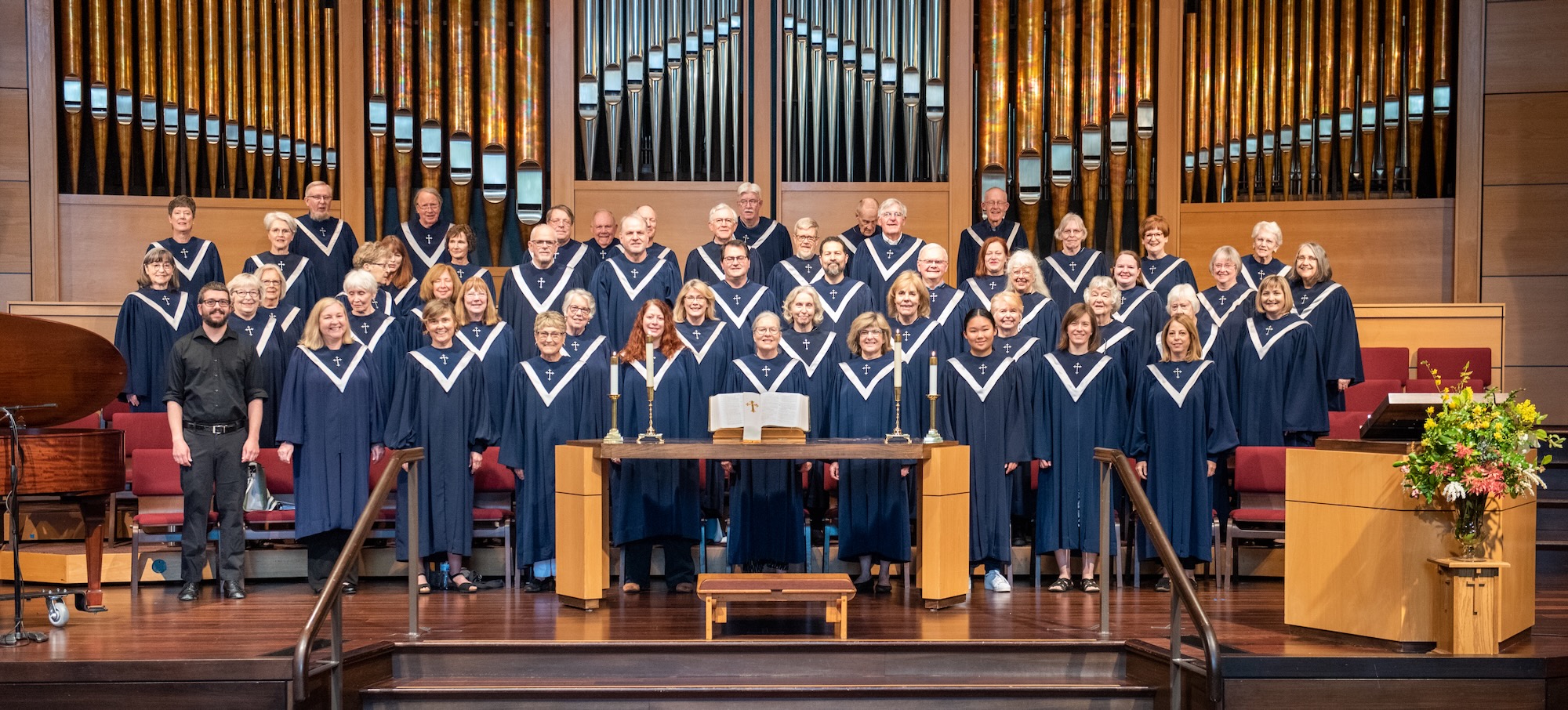 a wide view of the sanctuary choir in blue robes with organ pipes in the background