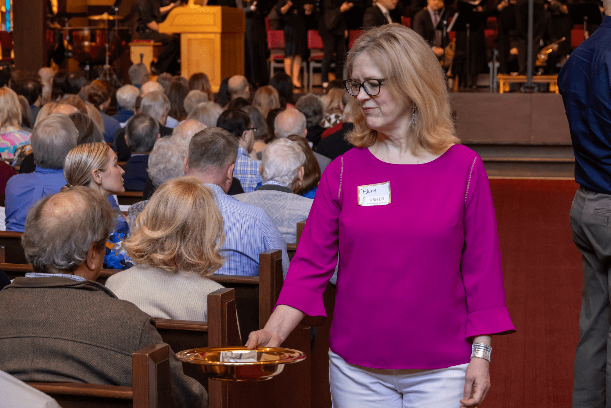 a volunteer usher passing the collection plate